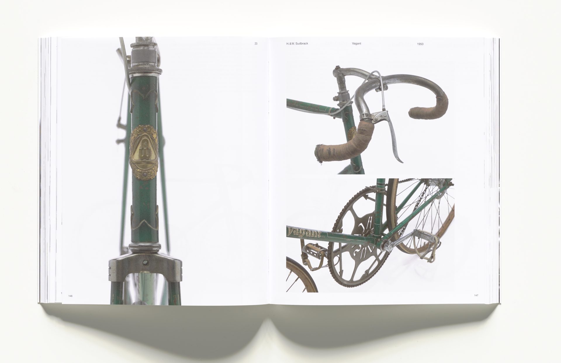 Photo of the open exhibition catalogue. On two pages are close-ups of a green sports bike: handlebars, handlebars and chain with two wheels.