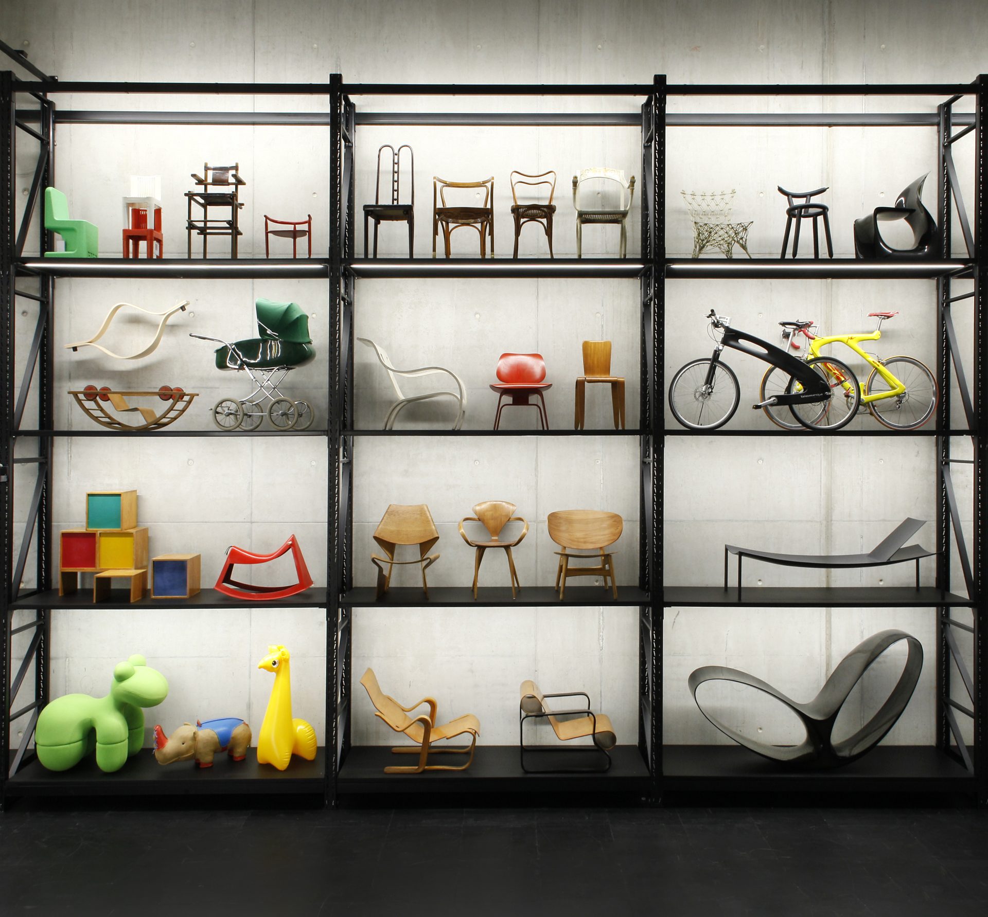 On display is a heavy-duty shelf with various children's furniture such as small chairs in various shapes and colors, baby carriages and plastic objects.