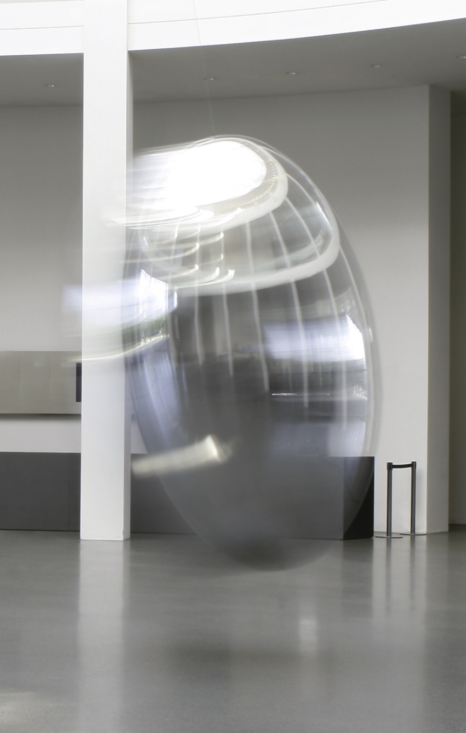 Das überdimensionierte Objekt Pendulum aus hochpoliertem Aluminium die umgebende Architektur spiegelnd