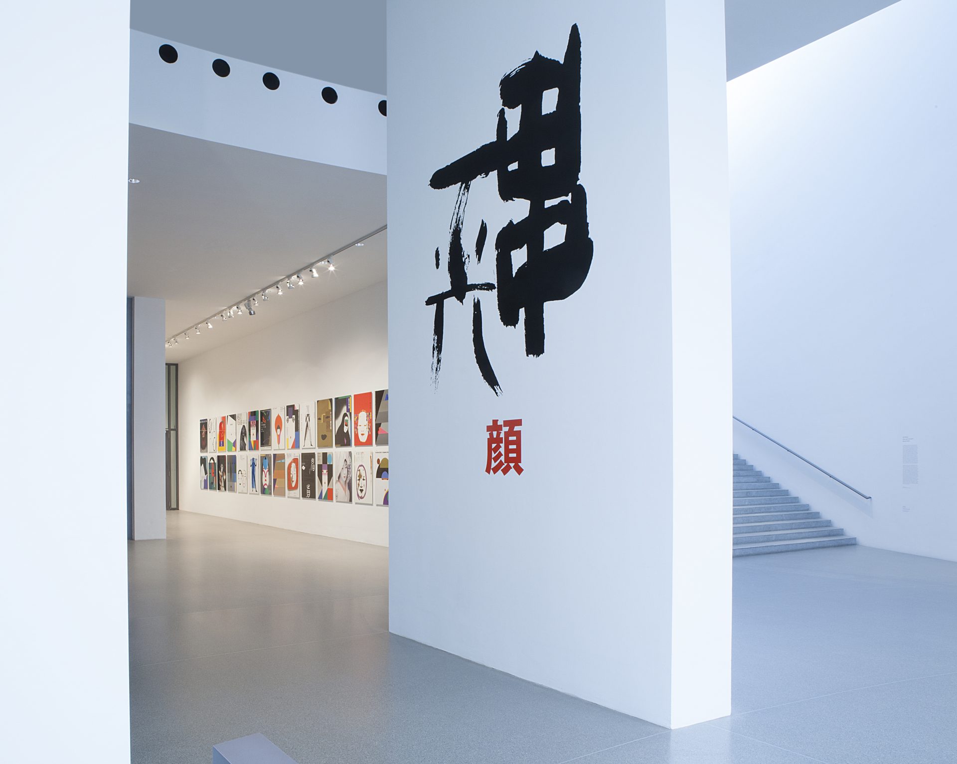 View of the corridor with posters and the wall with Japanese lettering: Ikko Tanaka: Faces. Posters.