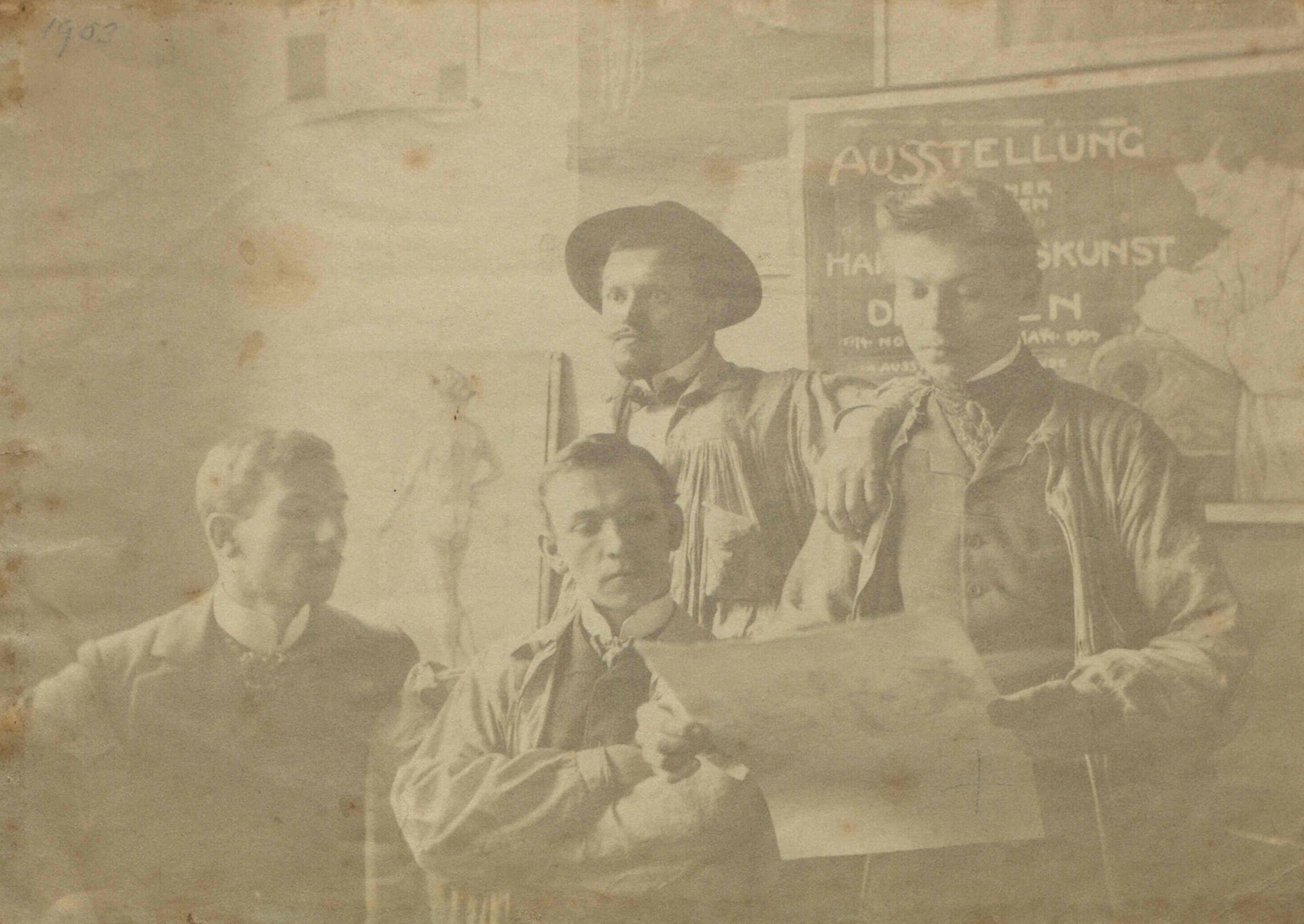 Alte Fotografie von 4 Männern an der Königlich-Sächsischen Kunstgewerbeschule Dresden, im Hintergrund Studien und Tafel zu Ausstellung.