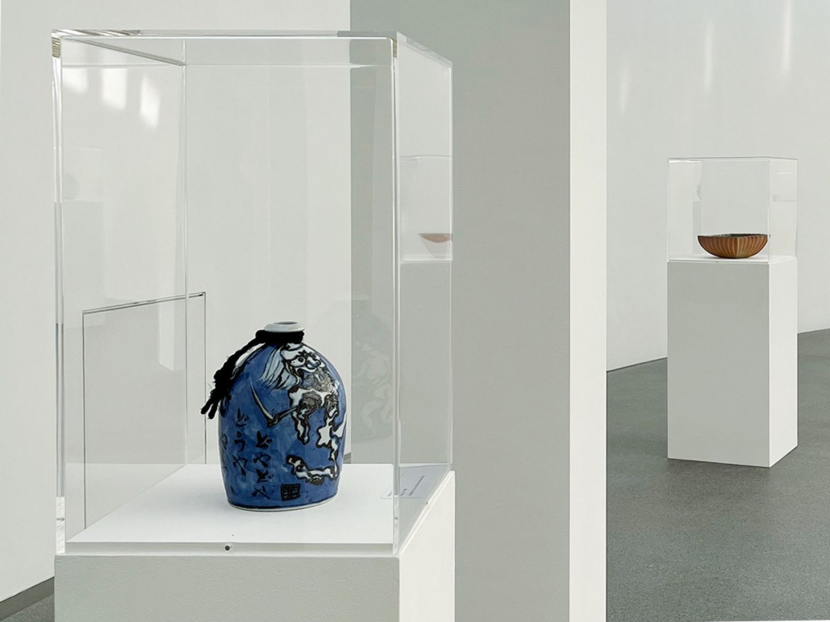 Photo of the exhibition room with two showcases. The showcase in the foreground contains a blue-framed vessel. The display case in the background contains a shallow bowl with striped decoration.