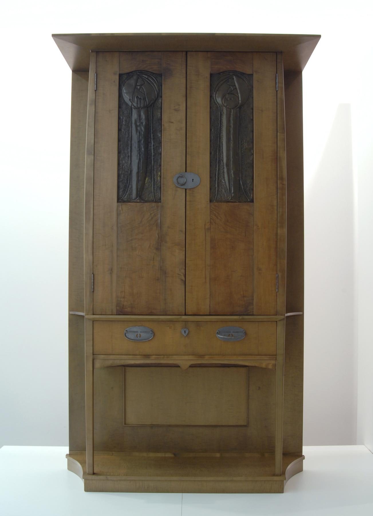 Wooden cabinet with ornate doors, metal fittings and an integrated drawer in the lower section.