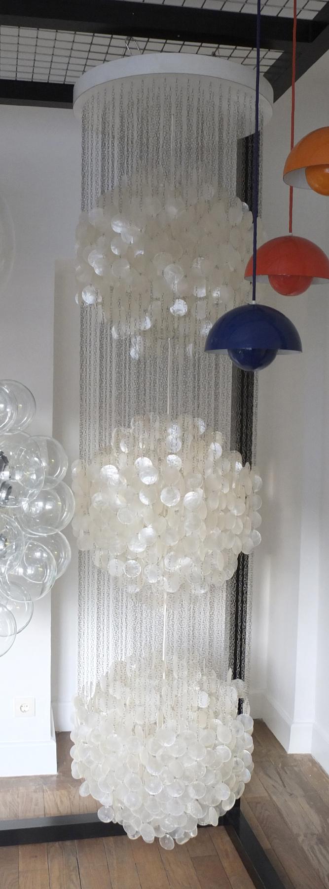 Tall, multi-level pendant light with round, shimmering shell plates on fine chains arranged in spherical clusters.