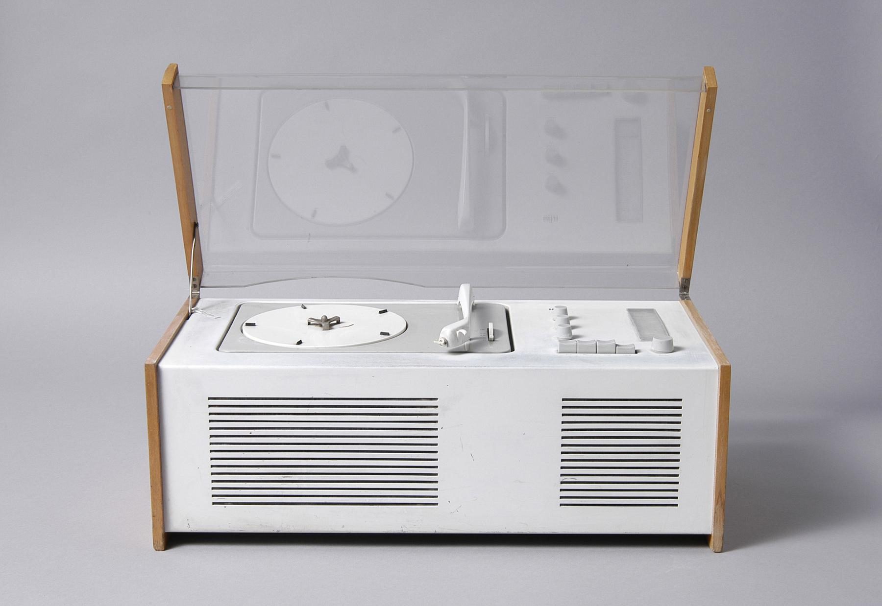 Open white record player with wooden side panels, integrated speakers and transparent cover. Minimalist design with white controls.