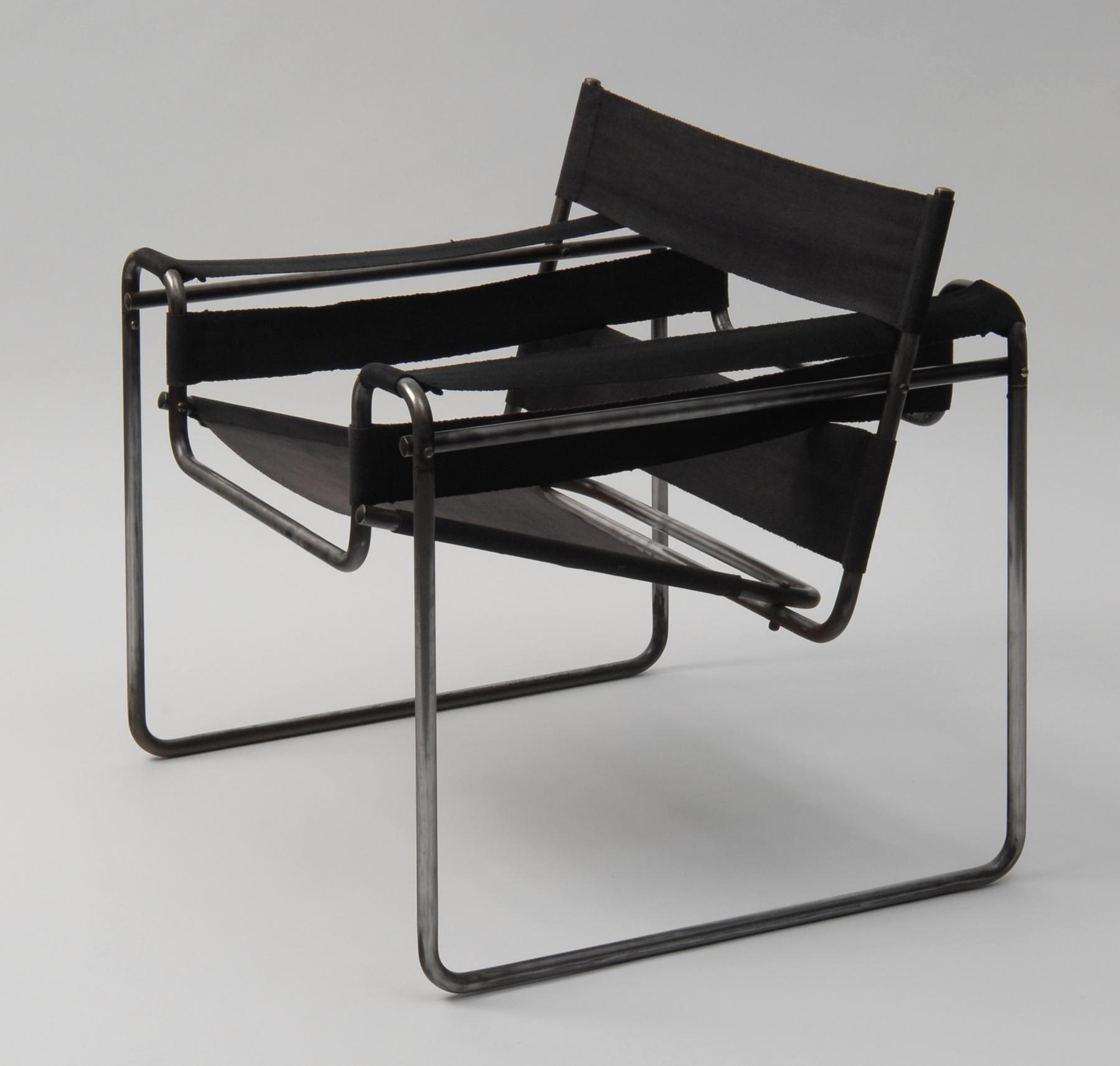 Photo Chair with metal frame and black fabric panels that form the seat, backrest and armrests.