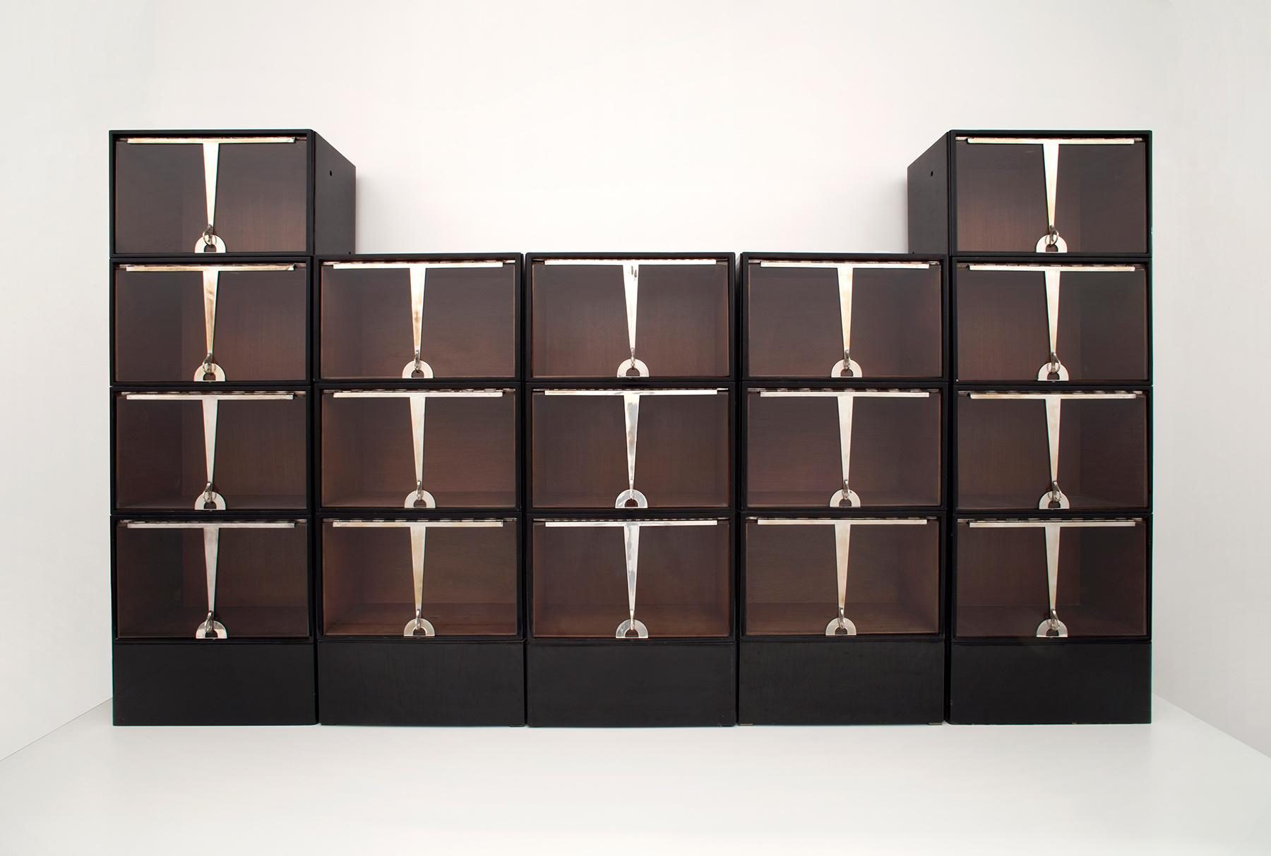 Symmetrical storage system with dark compartments and silver, geometric handle details on the fronts.