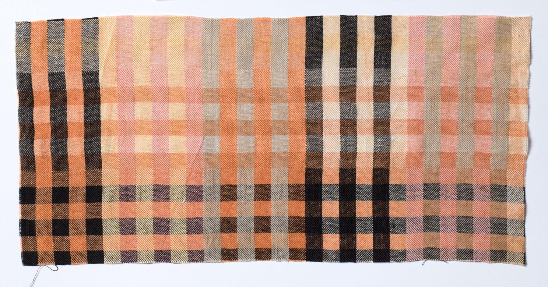 Foto einer Stoffprobe. Das Textil hat ein Webmuster aus gleich breiten Streifen. Die Streifen haben die Farben Schwarz, Rosa, Orange, Grau uns Beige.