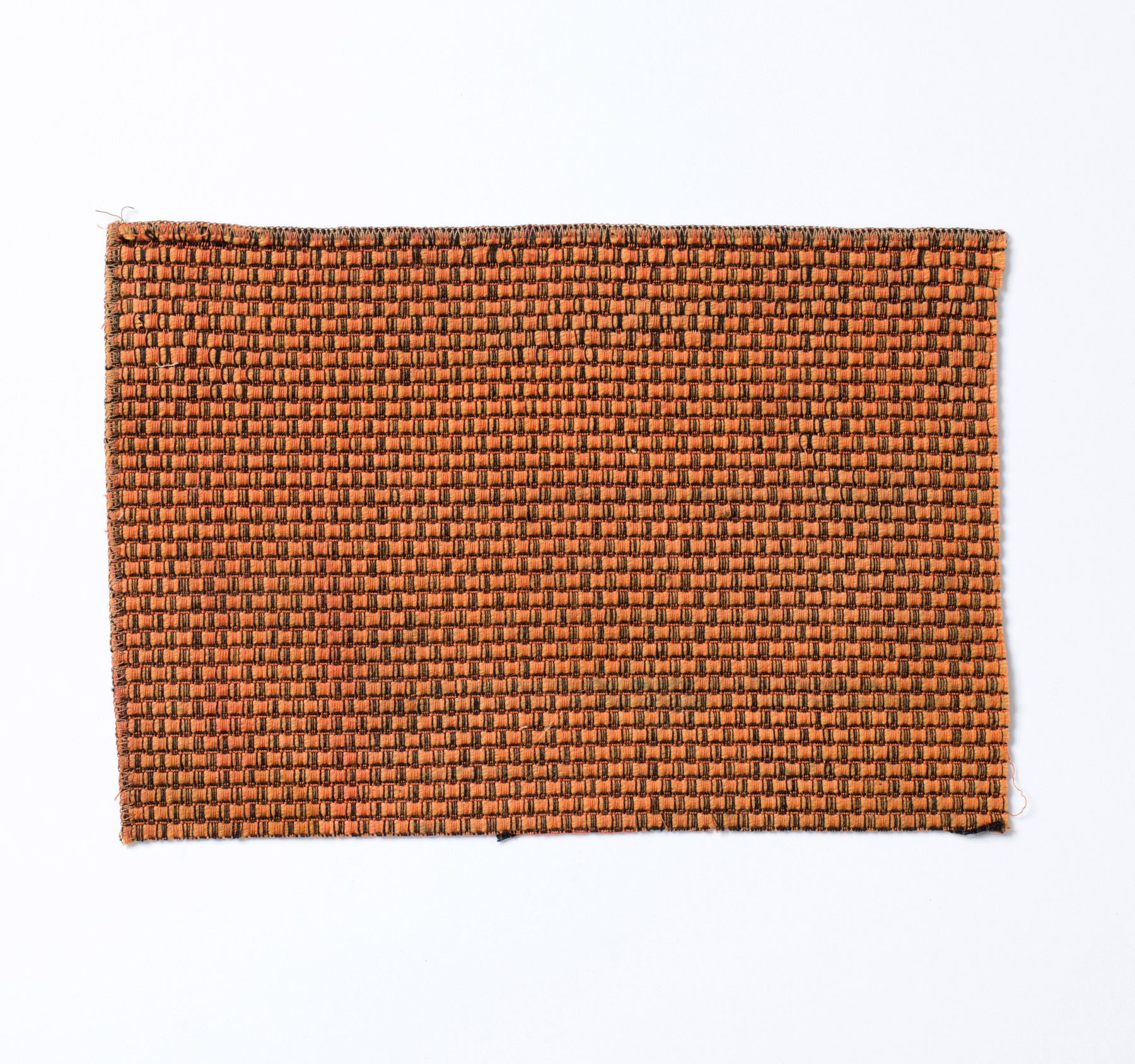 Photo of fabric. Rectangular piece made of a relatively coarse but dense orange-black weave pattern.