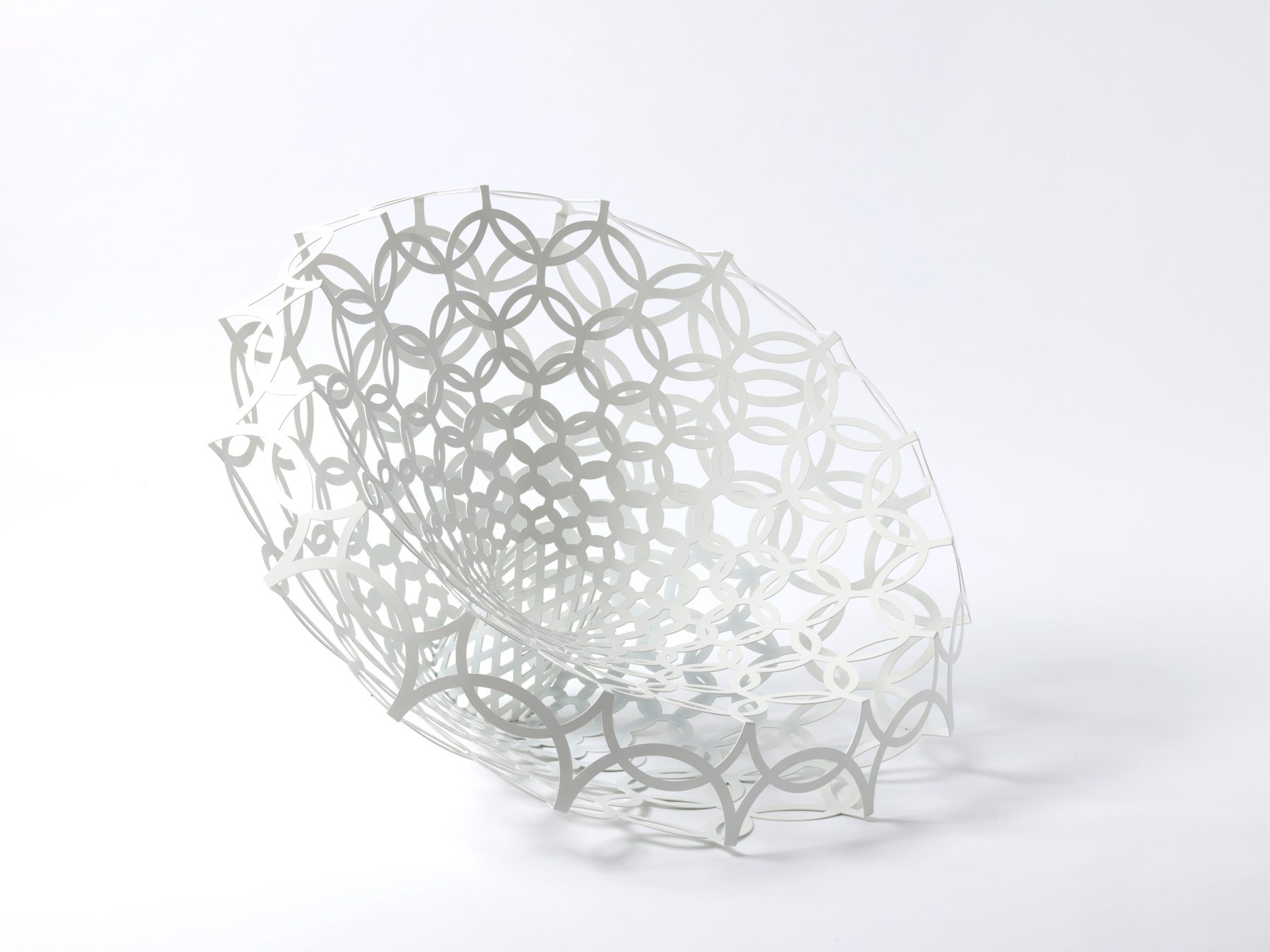 Armchair made of white, filigree laser-cut metal, consisting of intertwined circular shapes. The structure is light and openwork, with a geometric, symmetrical pattern.