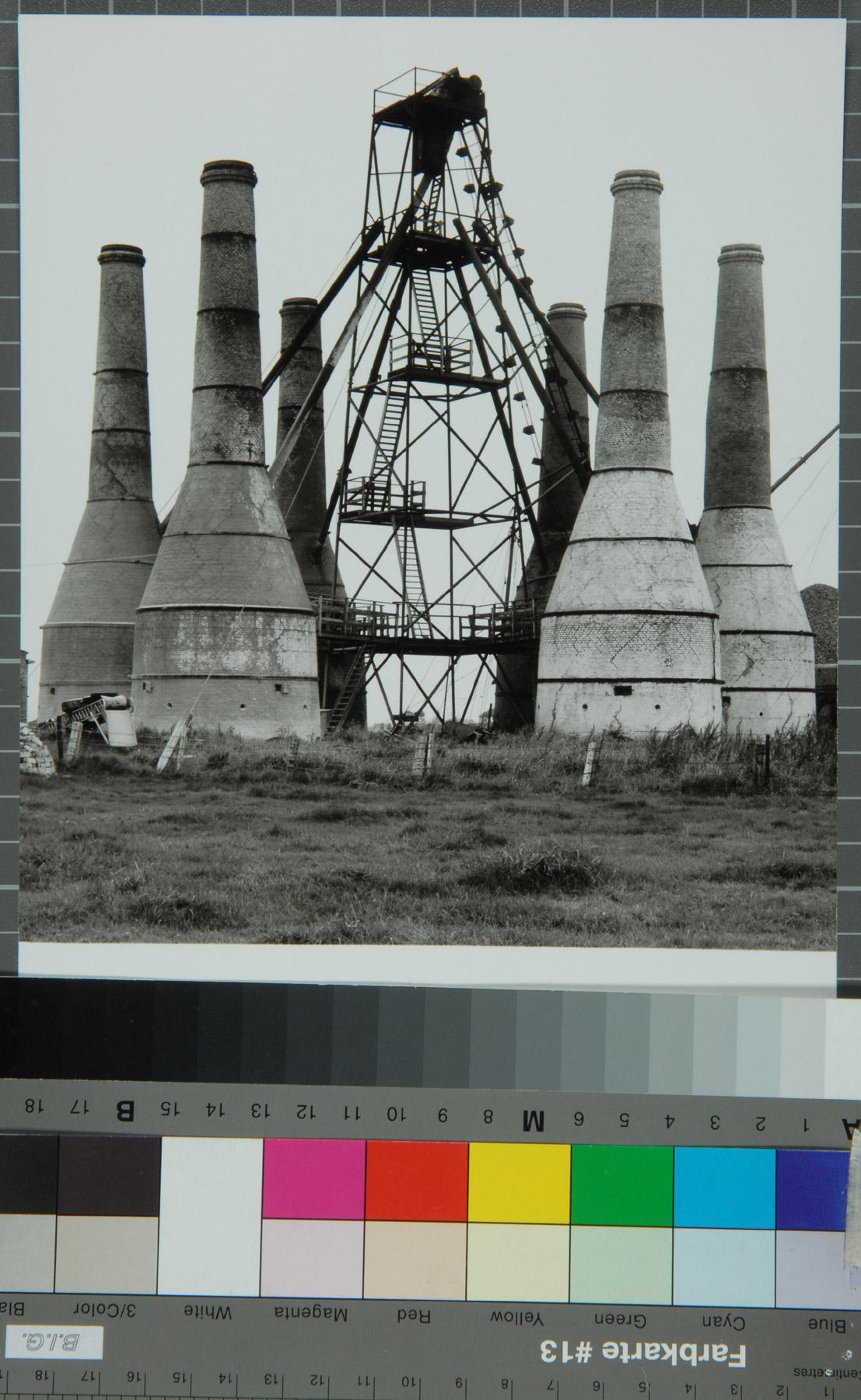 Industriegebäude mit Schornsteinen und Gerüst.