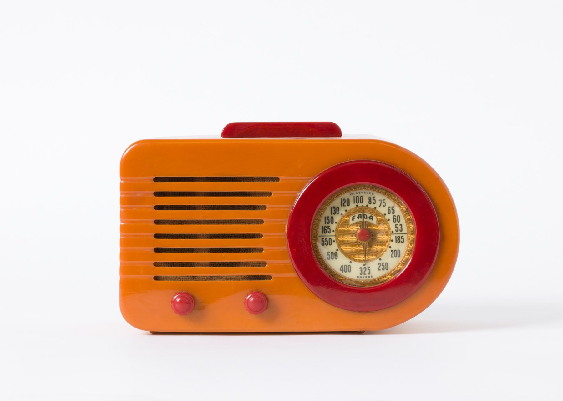 Radio mit einem Gehäuse in Orange und roten Akzenten. Rechts befindet sich eine runde, rot umrandete Frequenzanzeige mit goldenen Details, während links horizontale Schlitze und zwei rote Bedienknöpfe angeordnet sind.